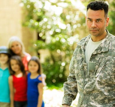 Stock image of uniformed service member walking away from wife and children