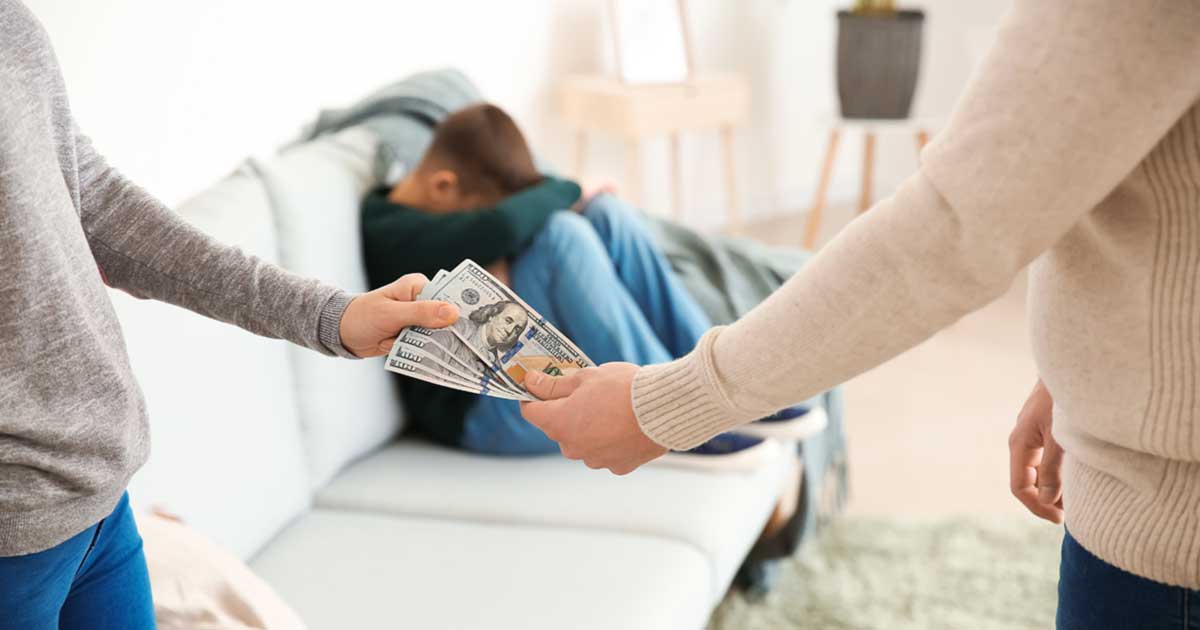 photo of parents exchanging money to illustrate article titled What happens if your ex misses a child support payment?