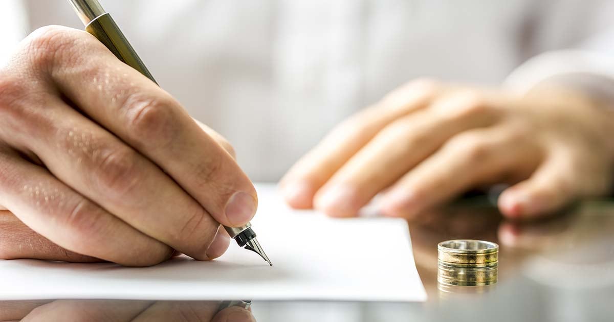 hand signing divorce papers to illustrate story on finalizing divorce